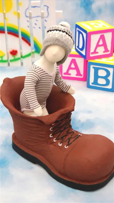 Posable infant mannequin displayed inside oversized boot prop for visual merchandising