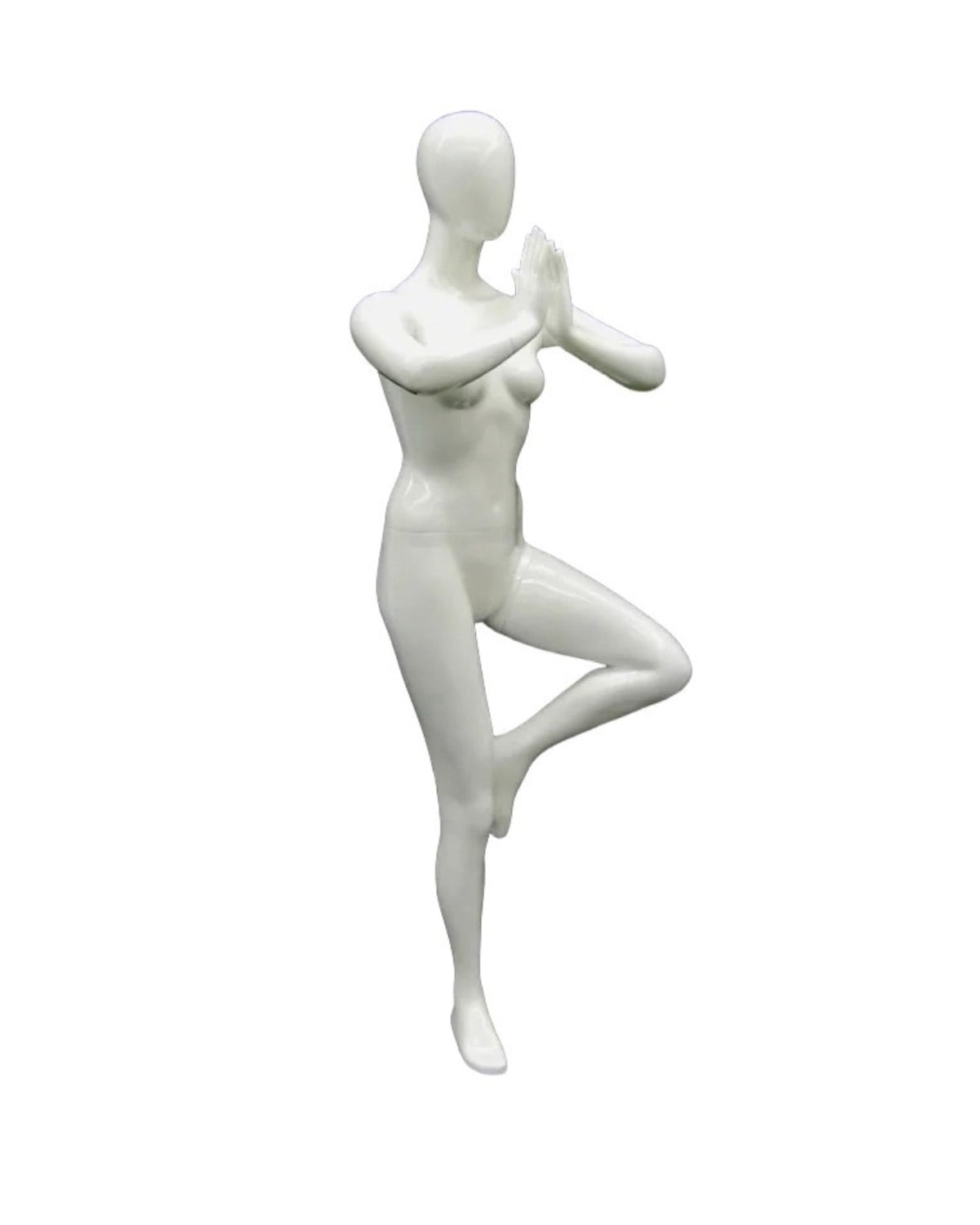 Posable female yoga mannequin in white practicing tree pose, showcasing flexibility and balance for display or photography.