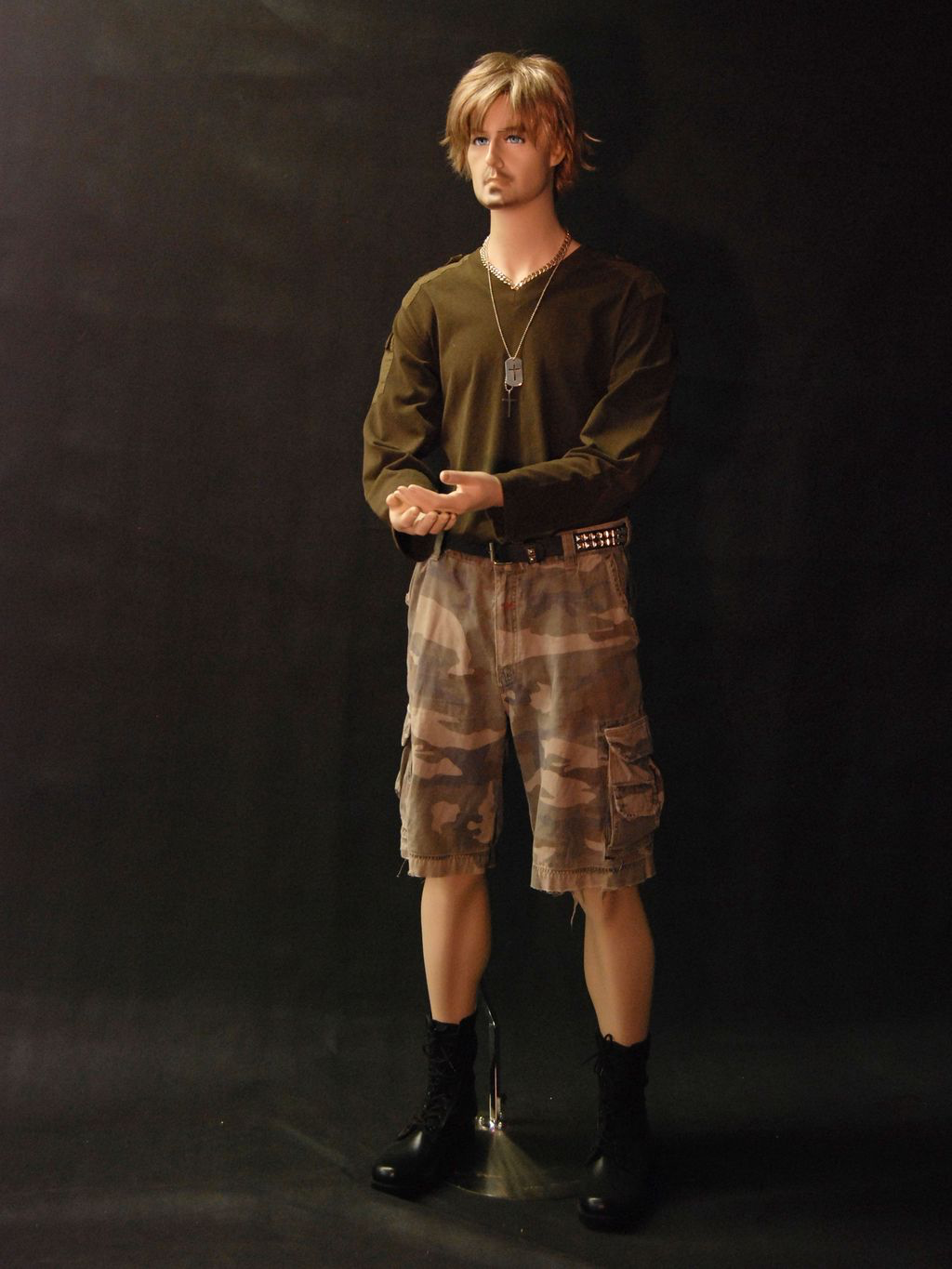 Mannequin wearing a green shirt and camouflage shorts against a black background